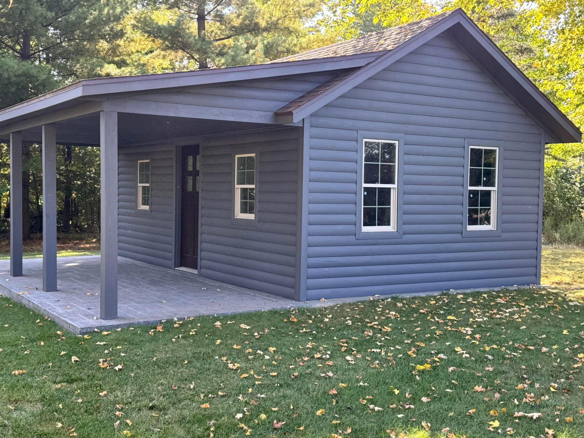 New guest cabin with covered porch, log siding, and stone paver patio