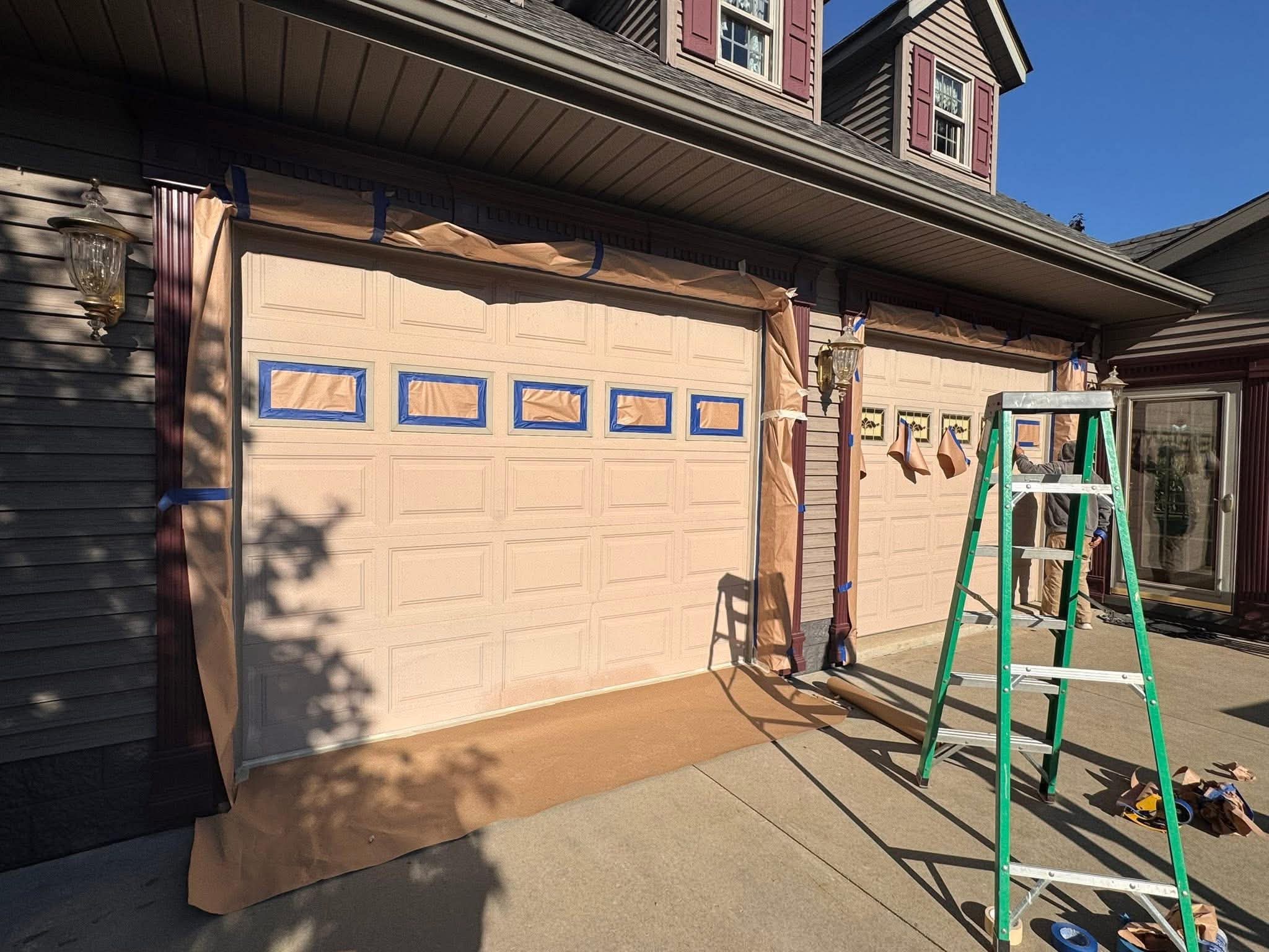 Garage doors masked and prepped with paper and tape ahead of repainting