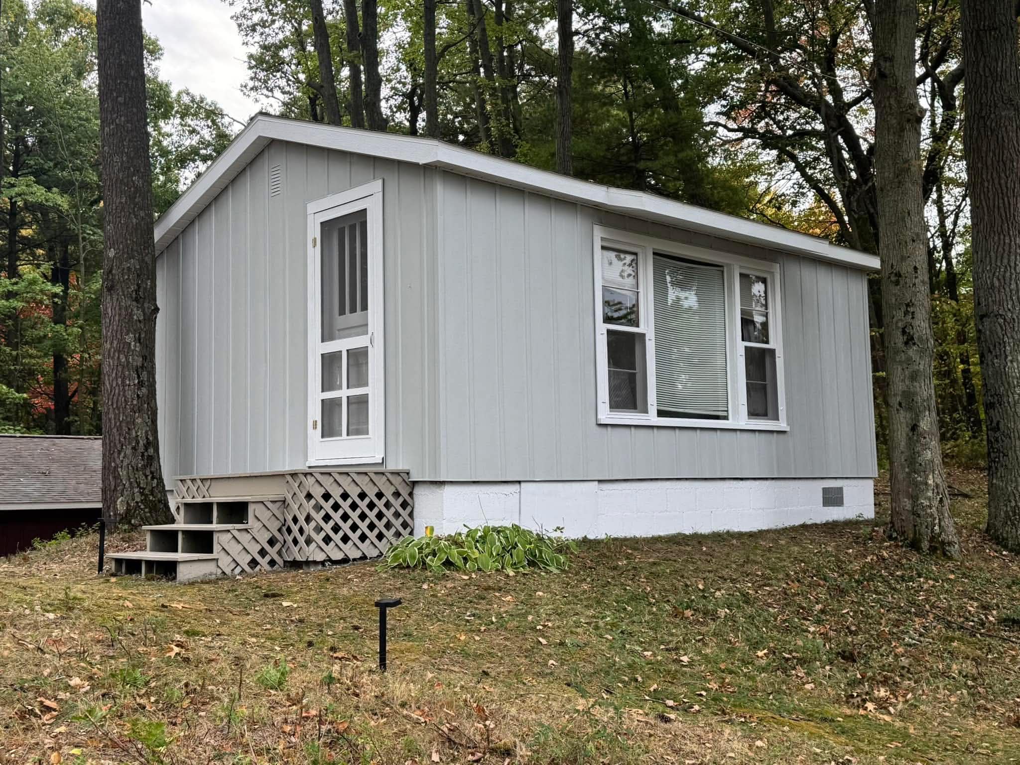 Same cabin after exterior stain and refinish, with a freshly painted white door