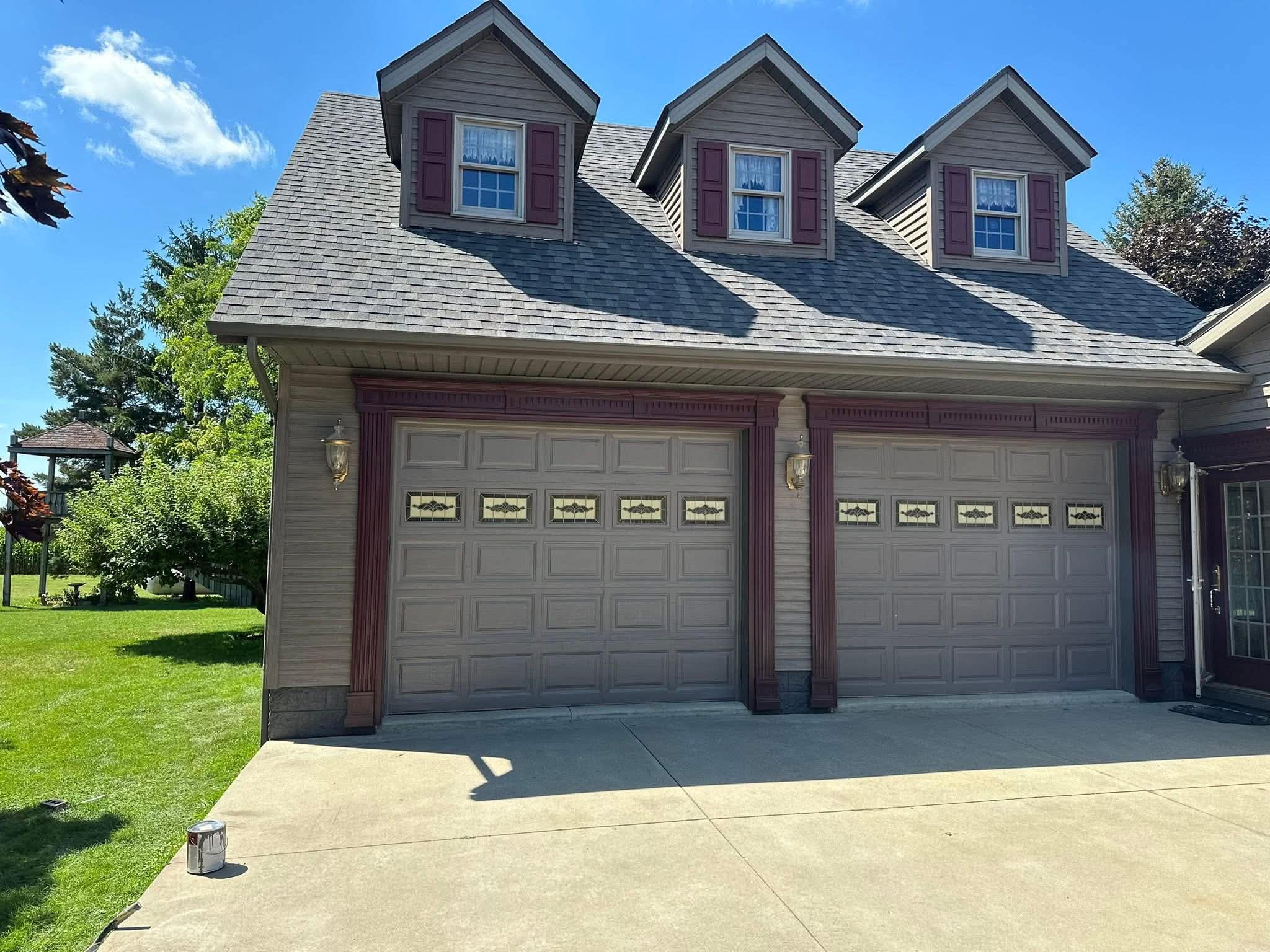 Two-story home with triple dormers and burgundy trim after exterior repaint
