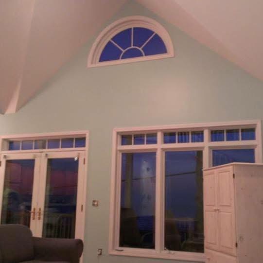 Vaulted living room with teal walls, arched transom window, and white French doors
