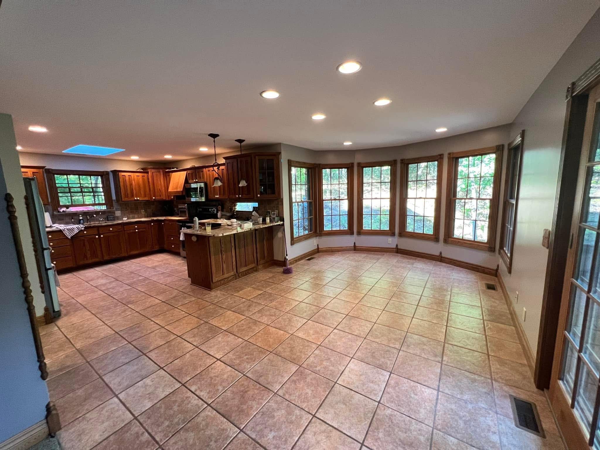 Open-concept kitchen and dining area with tile flooring and wall of windows
